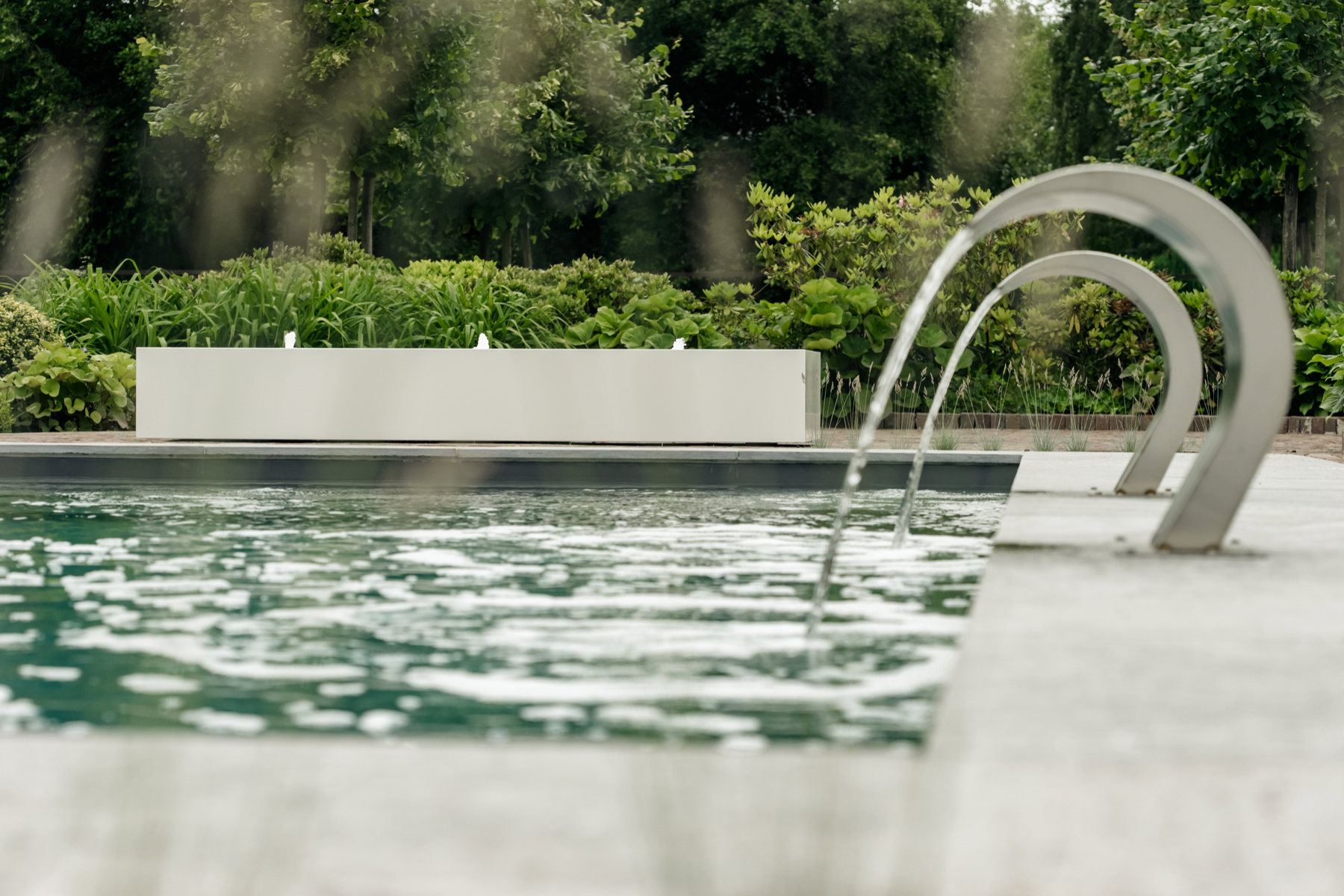 Dit zwembad krijgt een eigentijds karakter door de aanwezigheid van dit strakke waterornament.